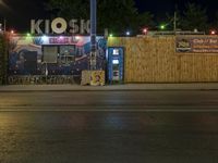 a street at night with no traffic on it's side and signs in front