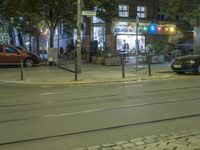 a city street has lights, vehicles and buildings in it at night time as cars wait