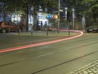 a city street has lights, vehicles and buildings in it at night time as cars wait