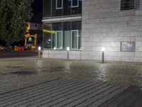 street lights on the sidewalk and a brick wall behind them that is empty outside with a small area of water around