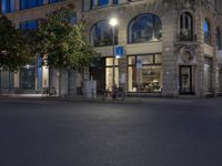 cars and bicyclists are driving along this empty street in front of many old buildings