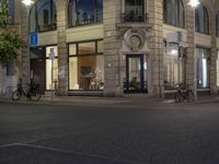 cars and bicyclists are driving along this empty street in front of many old buildings