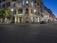 cars and bicyclists are driving along this empty street in front of many old buildings