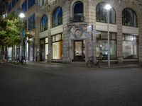 cars and bicyclists are driving along this empty street in front of many old buildings
