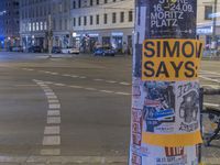 street sign post covered with stickers and posters on the corner of the street,