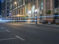 a city street with cars driving on it at night with light trails from a clock tower