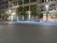 a red fire hydrant on a street corner by some tall buildings at night with bright lights