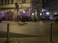 people are eating outside the outdoor dining area at night time, with a light on