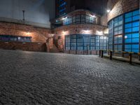 some dark blue windows in an industrial building with no one on the street to the right