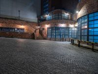 some dark blue windows in an industrial building with no one on the street to the right