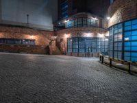 some dark blue windows in an industrial building with no one on the street to the right