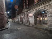 an old street is lit at night with a sign on the corner in front of it