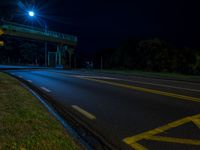 an empty highway is lit by street lights at night time, with no traffic or pedestrians