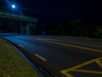 an empty highway is lit by street lights at night time, with no traffic or pedestrians