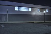 the side of a building at night with street lights lite up outside, as seen from behind