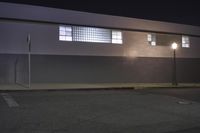 the side of a building at night with street lights lite up outside, as seen from behind