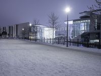 people are walking in the snow on a snowy road at night and an old building with lights