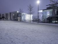 people are walking in the snow on a snowy road at night and an old building with lights