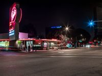 a city street lit up at night in the usa with the lights on and stores lining both sides of the road