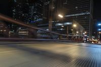 the blurry shot of an empty street at night shows off many tall buildings and buildings