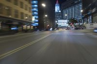 the blurred image of an intersection at night with skyscrapers in background and cars driving on the road