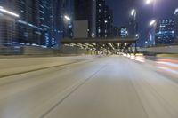 a motion blur photo of some buildings on a freeway with light traffic at night time