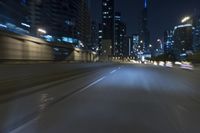 a freeway in the city at night time with cars moving and skyscrapers on both sides