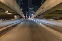 the car is driving over the bridge at night in traffic lights, traffic, skyscrapers, cars