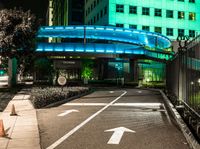 a pedestrian crossing in a city at night with two building and green lights behind it