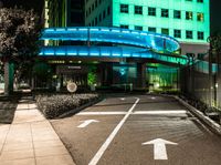 a pedestrian crossing in a city at night with two building and green lights behind it