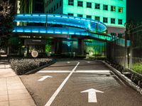 a pedestrian crossing in a city at night with two building and green lights behind it