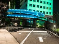 a pedestrian crossing in a city at night with two building and green lights behind it