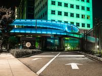 a pedestrian crossing in a city at night with two building and green lights behind it