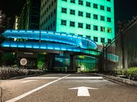 a pedestrian crossing in a city at night with two building and green lights behind it