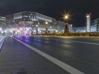 a car travels along an empty street at night at a city centre in europe, near a busy street lights