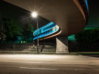 an illuminated tunnel on the side of a road at night, with a bike on the pavement