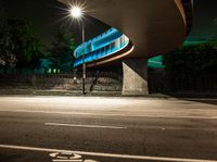 an illuminated tunnel on the side of a road at night, with a bike on the pavement