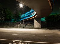 an illuminated tunnel on the side of a road at night, with a bike on the pavement