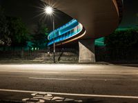 an illuminated tunnel on the side of a road at night, with a bike on the pavement