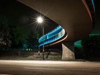 an illuminated tunnel on the side of a road at night, with a bike on the pavement