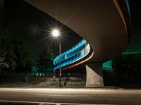 an illuminated tunnel on the side of a road at night, with a bike on the pavement