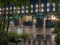 a large brick sidewalk with a store front at night time and a sign that says