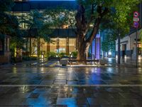 a large brick sidewalk with a store front at night time and a sign that says