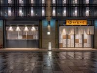 a large brick sidewalk with a store front at night time and a sign that says