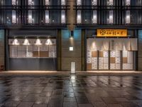 a large brick sidewalk with a store front at night time and a sign that says