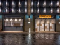 a large brick sidewalk with a store front at night time and a sign that says