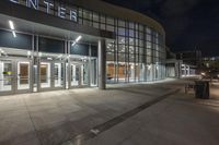 a photo of an empty building with large entrance at night with people walking by it