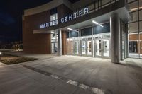 a photo of an empty building with large entrance at night with people walking by it