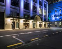 a street lit up in blue lighting and some buildings at night time and a road with parking meters between it