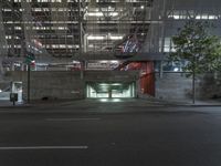 a empty parking garage under an indoor bridge on a city street at night time, in the middle of a wide street
